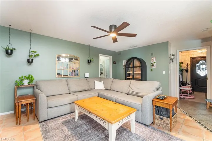 Tiled living room with visible vents, baseboards, and ceiling fan