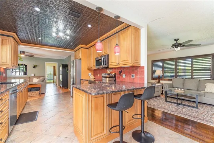 Kitchen featuring open floor plan, a wealth of natural light, stainless steel appliances, a ceiling fan, and a sink