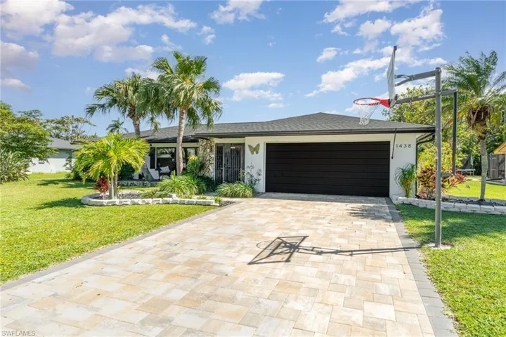 Ranch-style home featuring stucco siding, an attached garage, decorative driveway, and a front lawn