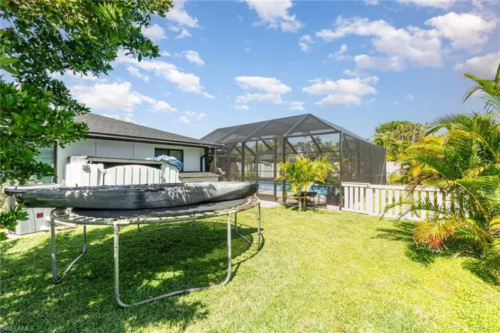 View of yard featuring a lanai, fence, pet friendly side yard and an outdoor pool