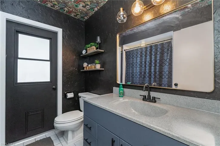 Full secondary bathroom featuring vanity, tile patterned floors, curtained shower, and toilet