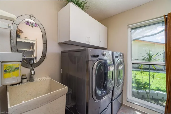 Clothes washing area featuring cabinet space, independent washer and dryer, and a sink