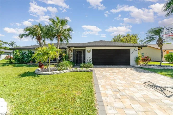 View of front of house with decorative driveway, a front lawn, an attached garage, and stucco siding