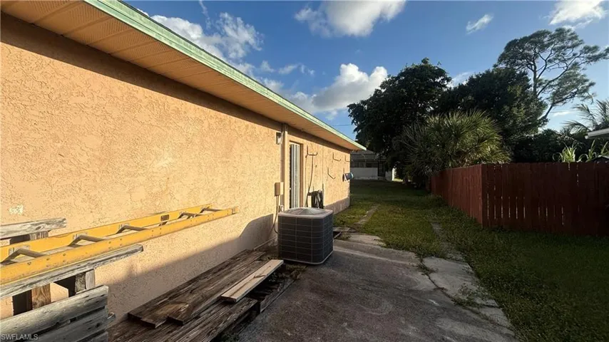 Stucco exterior side profile featuring a concrete walkway and wood-style privacy fencing