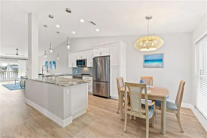 Kitchen featuring white cabinetry, quartz counters, stainless steel appliances, tasteful backsplash, and pendant lighting