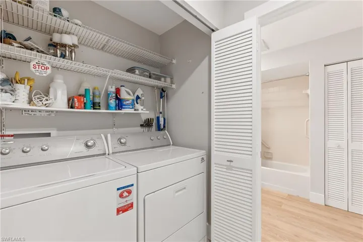 Laundry room featuring washer and clothes dryer, storage, and light wood-type flooring
