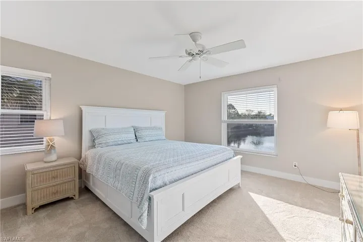 Master bedroom with lake views, ensuite bath, ceiling fan, and carpet