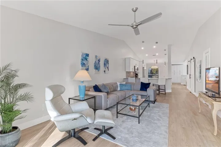 Living room with ceiling fan, light hardwood / wood-style floors, and vaulted ceiling