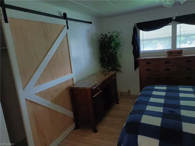 Bedroom featuring light wood-type flooring and a barn door