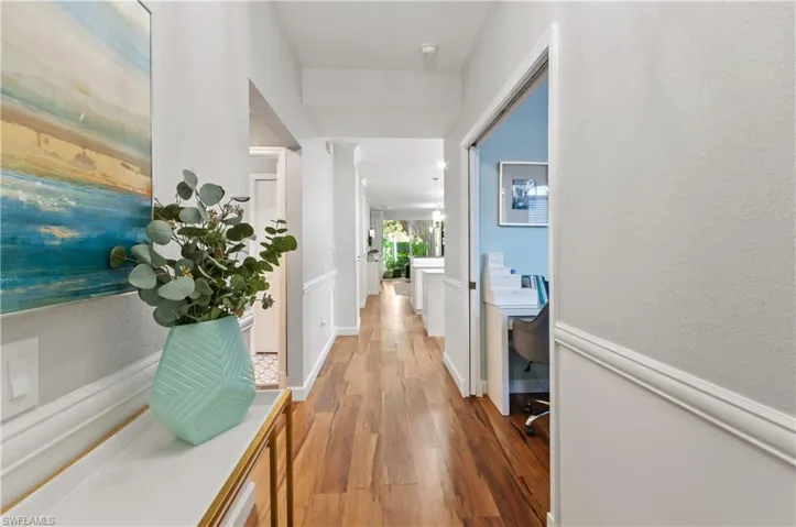 Corridor featuring light wood-style flooring and a textured wall