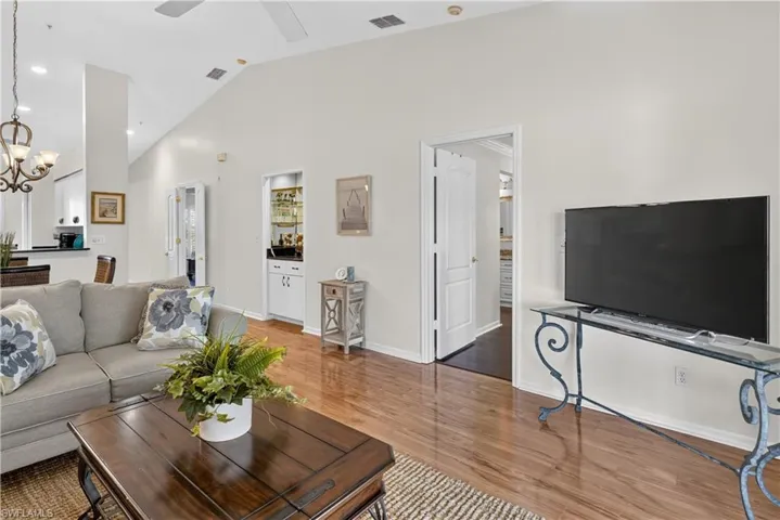 Vaulted ceiling, recessed lighting, wood-finish flooring, built-in bar cabinet, and white interior doors