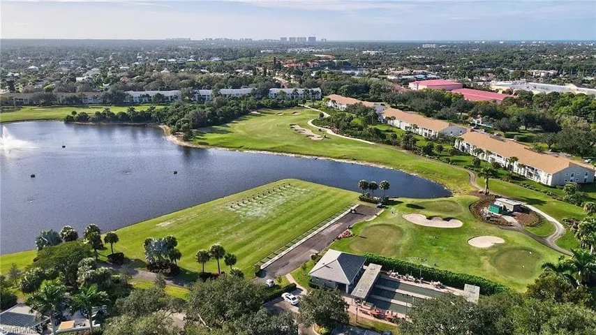 Expansive greenspace with a water feature, golf course, and multiple residential buildings