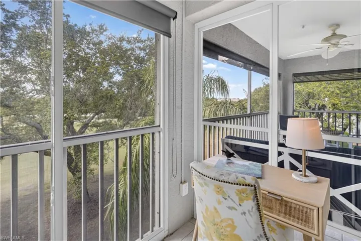 Screened-in balcony with white railings, a ceiling fan, and roll-down shades