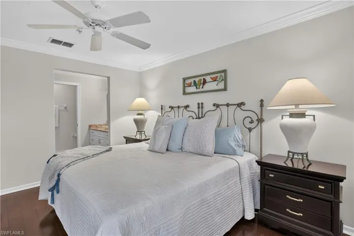 Dark wood-finish flooring, crown molding, and a ceiling fan with integrated lighting
