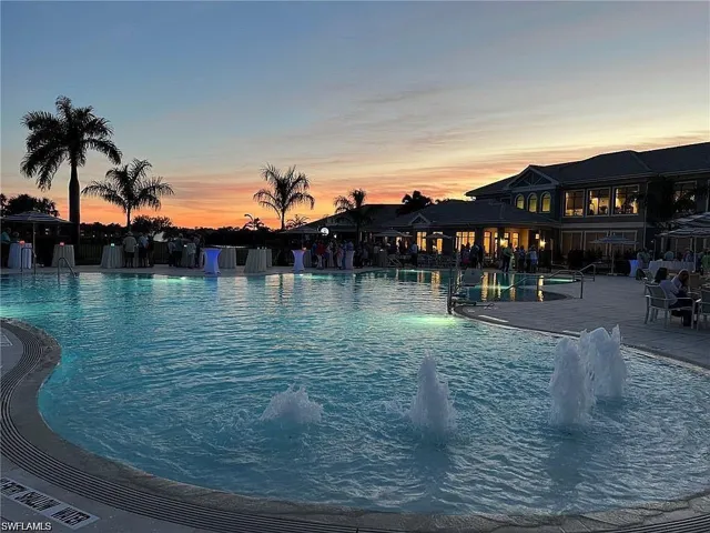 Expansive pool deck with a large swimming pool, water features, and surrounding palm trees