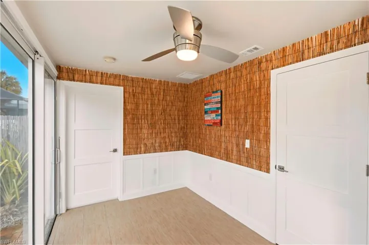 Spare room with a ceiling fan, a wainscoted wall, and a decorative wall