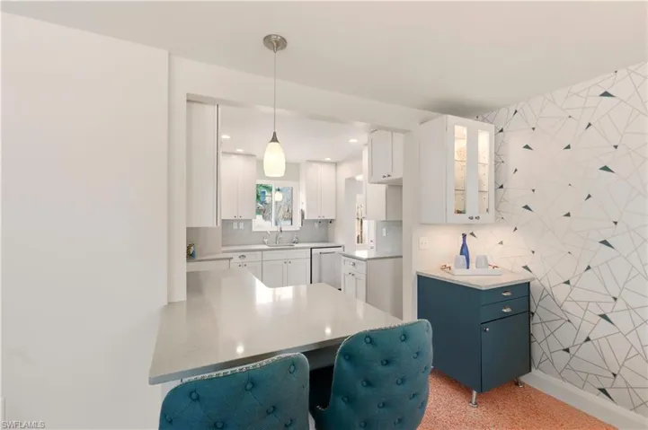 Kitchen featuring a breakfast bar, hanging light fixtures, glass fronted cabinets, a peninsula, and dishwasher