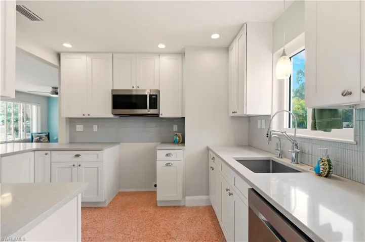 Kitchen featuring white cabinets, stainless steel appliances, and light stone counters