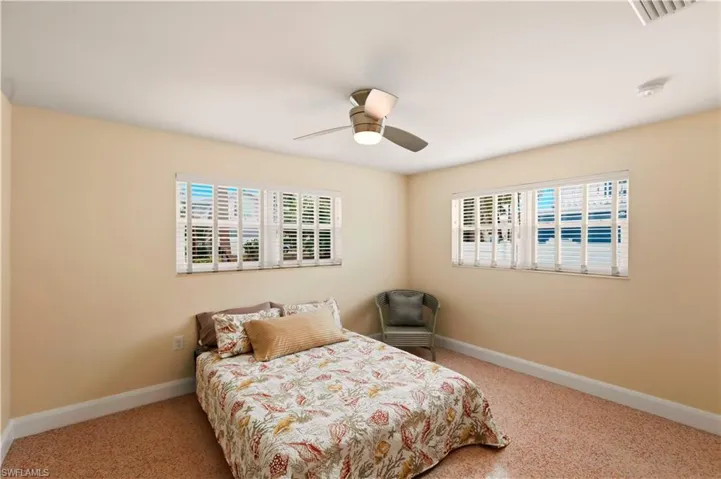 Bedroom with multiple windows, ceiling fan, and light carpet