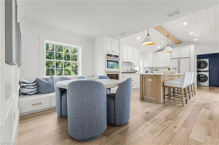 Dining space featuring vaulted ceiling, light wood finished floors, estacked washer and dryer, and recessed lighting