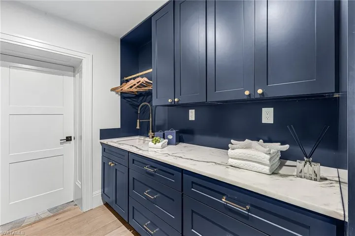 Bar featuring blue cabinetry, light wood-style flooring, and light stone countertops