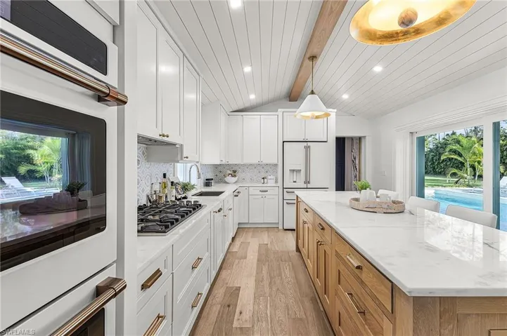 Kitchen featuring white cabinets, white appliances, light stone counters, light wood-style flooring, and recessed lighting