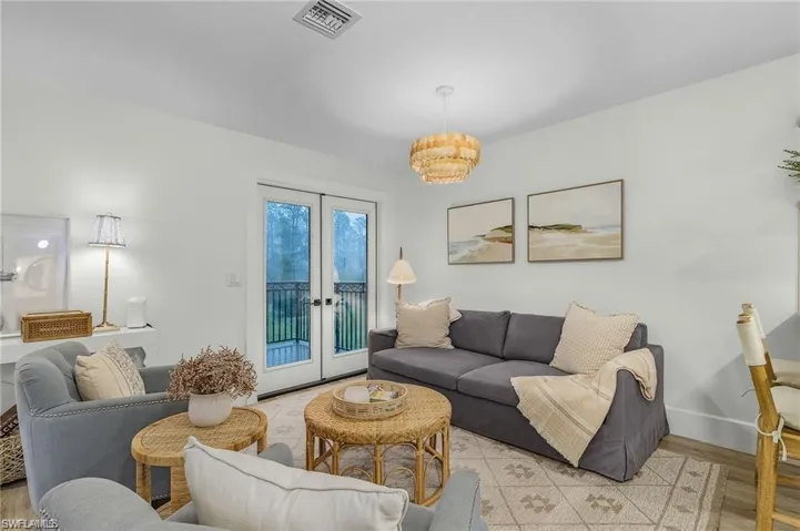 Living room with french doors, wood finished floors, and a chandelier