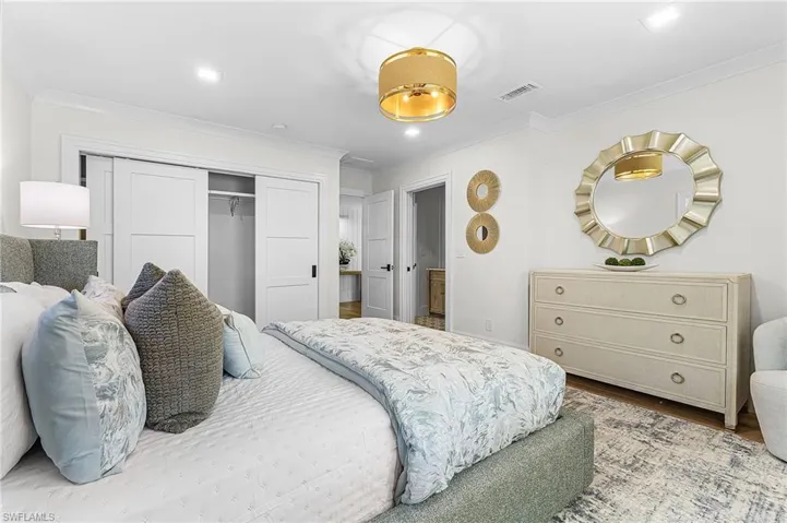 Bedroom featuring a closet, wood finished floors, ornamental molding, and recessed lighting