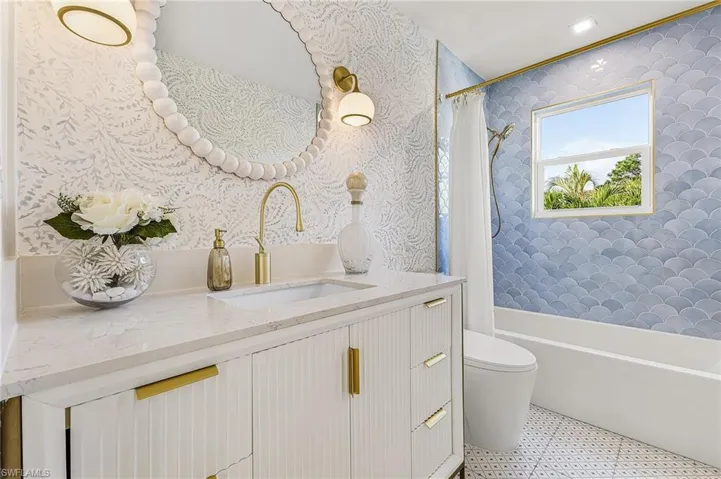 Bathroom featuring shower / bath combination with curtain, vanity, wallpapered walls, and light tile patterned floors