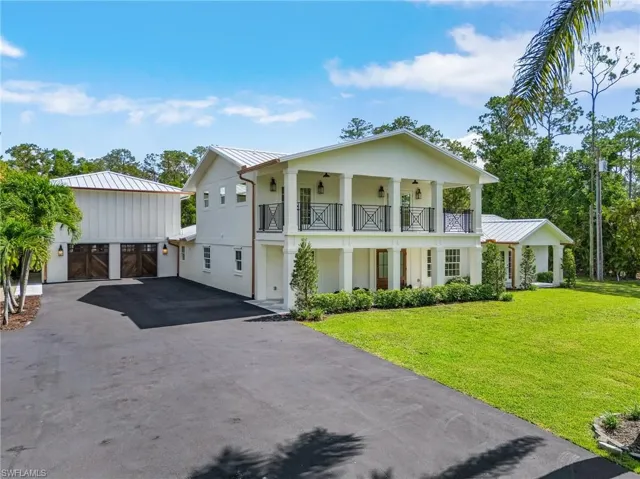 Greek revival house featuring a metal roof, a standing seam roof, a front lawn, driveway, and a porch
