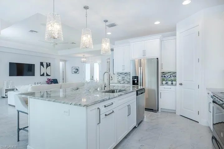 Kitchen with tasteful backsplash, white cabinets, sink, a center island with sink, and stainless steel appliances