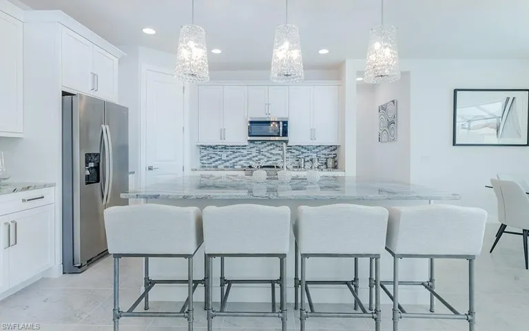 Kitchen with white cabinets, tasteful backsplash, appliances with stainless steel finishes, and light tile patterned flooring
