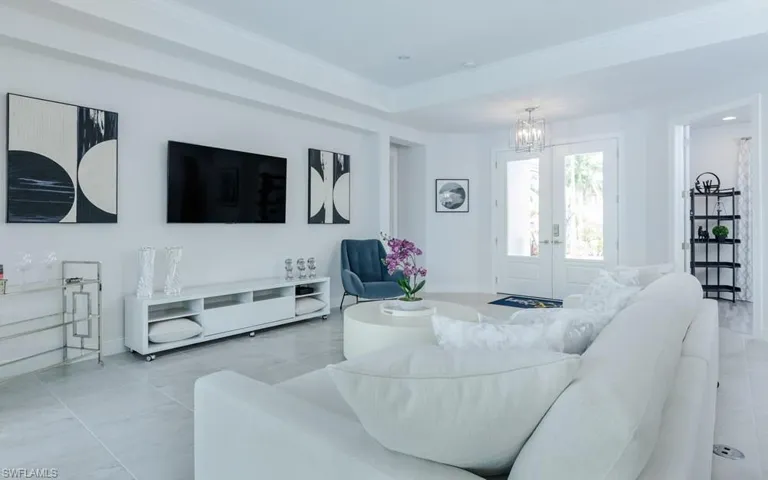 Tiled living room with a notable chandelier and a tray ceiling