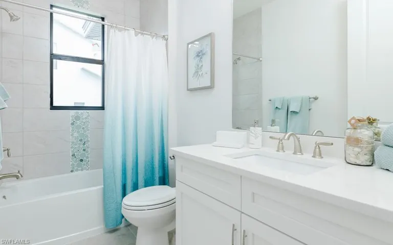 Full bathroom featuring tile patterned floors, toilet, vanity, and shower / bathtub combination with curtain