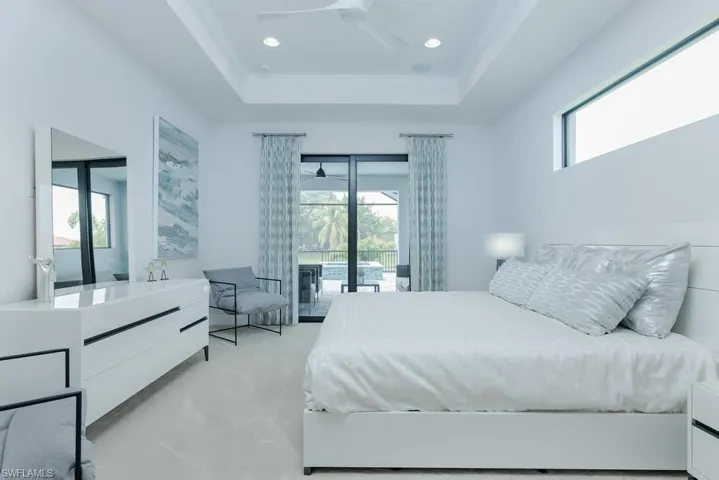 Bedroom featuring a tray ceiling, ceiling fan, access to outside, and light carpet