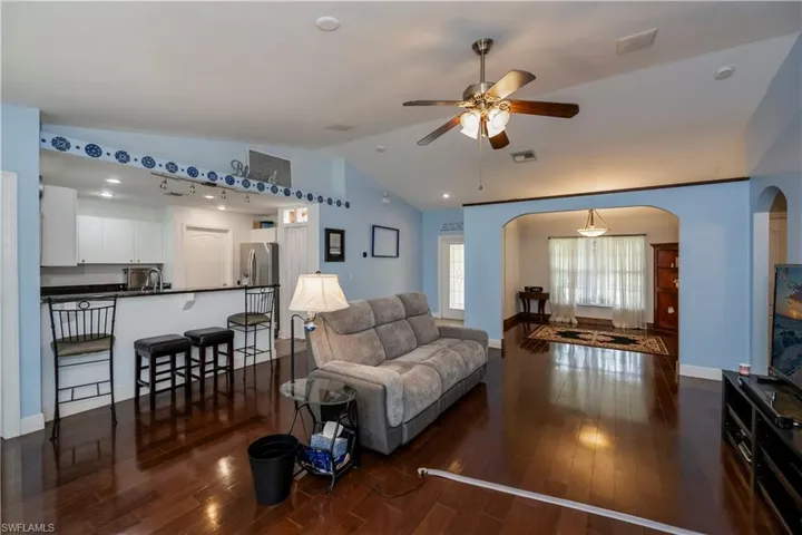 Living room with lofted ceiling, dark hardwood / wood-style floors, ceiling fan, and sink