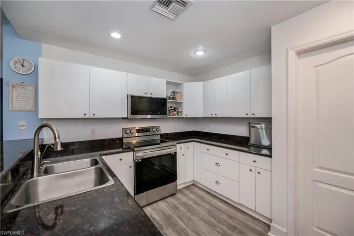Kitchen with white cabinets, light wood-type flooring, stainless steel appliances, and sink