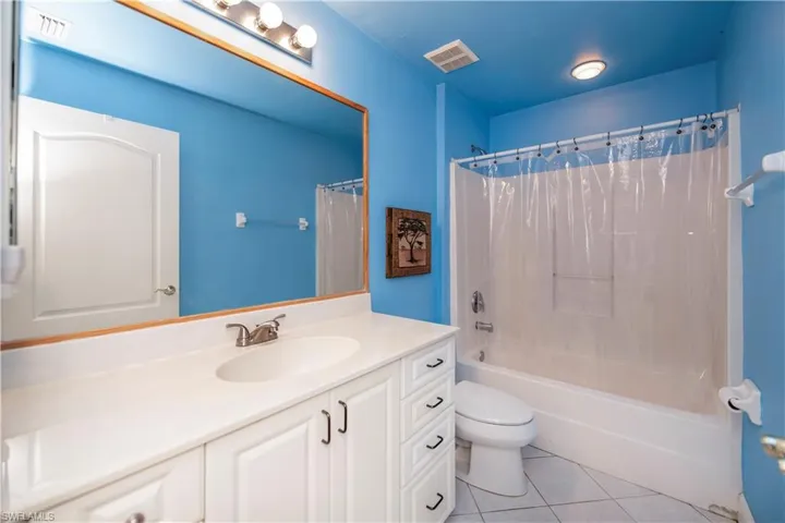 Full bathroom with vanity, tile patterned floors, toilet, and shower / bath combination with curtain