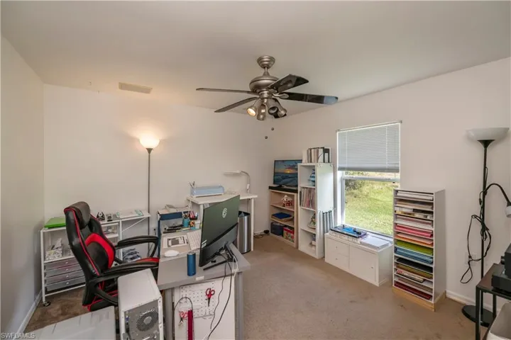 Carpeted office featuring ceiling fan
