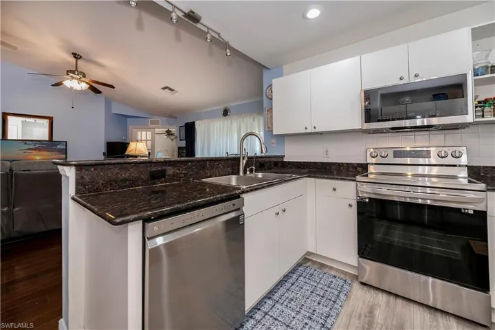 Kitchen featuring stainless steel appliances, sink, kitchen peninsula, white cabinets, and light wood-type flooring