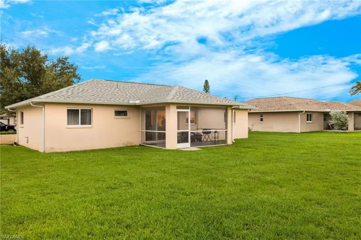 Rear view of property featuring a sunroom and a lawn