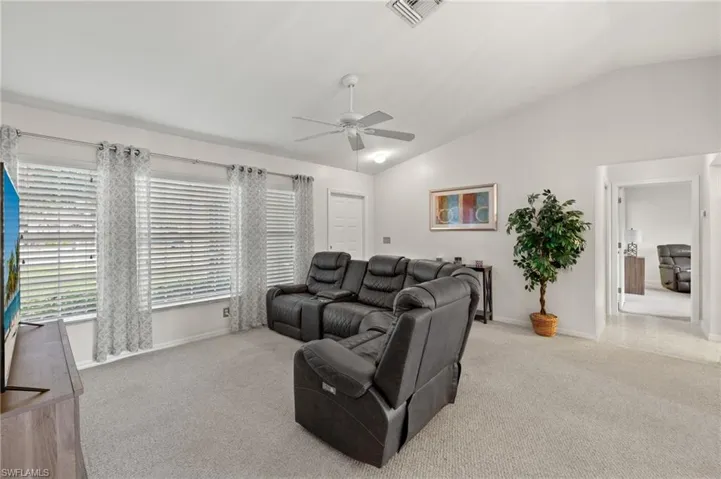 Living room with light carpet, ceiling fan, and vaulted ceiling