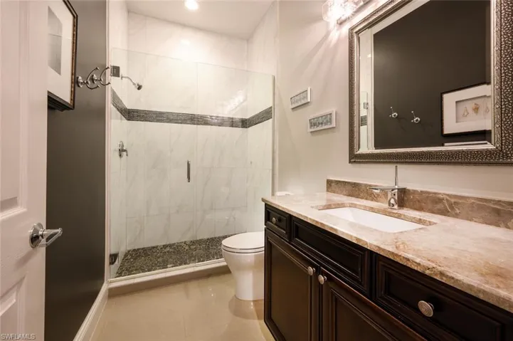 The guest bathroom with walk in tile shower, granite counter tops, designer lighting and mirror