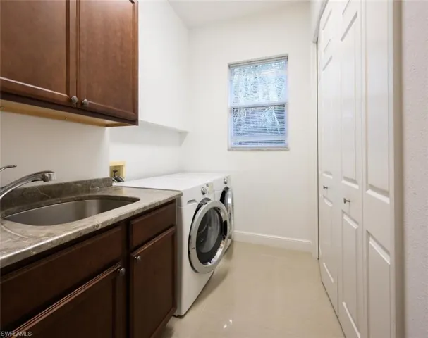 Spacious Laundry room with granite counter top, cabinet storage, front loader washer and dryer and large storage closet