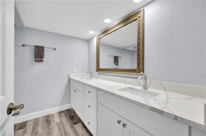 Primary bath featuring double vanity, light wood-type flooring, recessed lighting