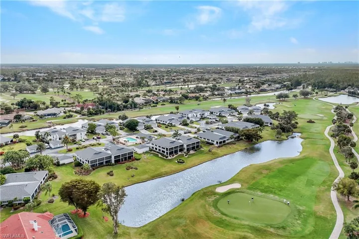 Aerial view of community area featuring a golf course and lake
