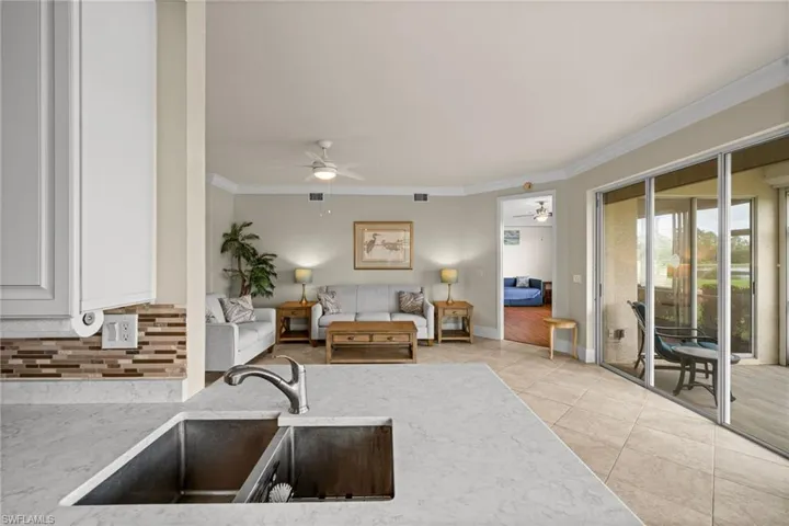 Living area featuring ornamental molding, light tile patterned floors, and ceiling fan