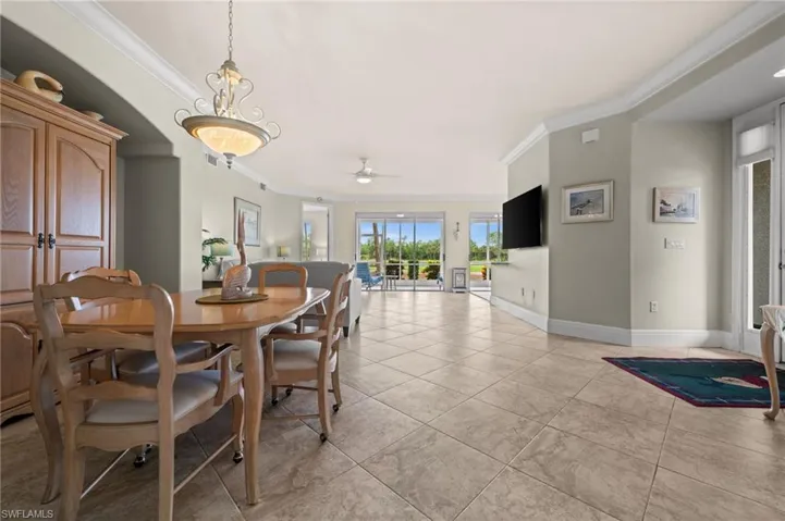 Dining room with crown molding, a ceiling fan, and light tile patterned floors