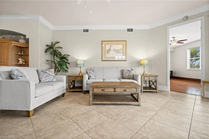 Living room featuring a ceiling fan, ornamental molding, and light tile patterned flooring