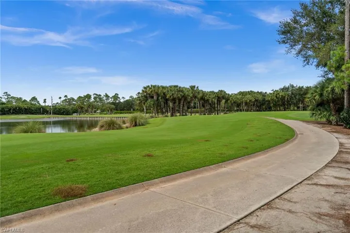 View of property's community featuring view of scattered trees, a water view, a lawn, and view of golf course